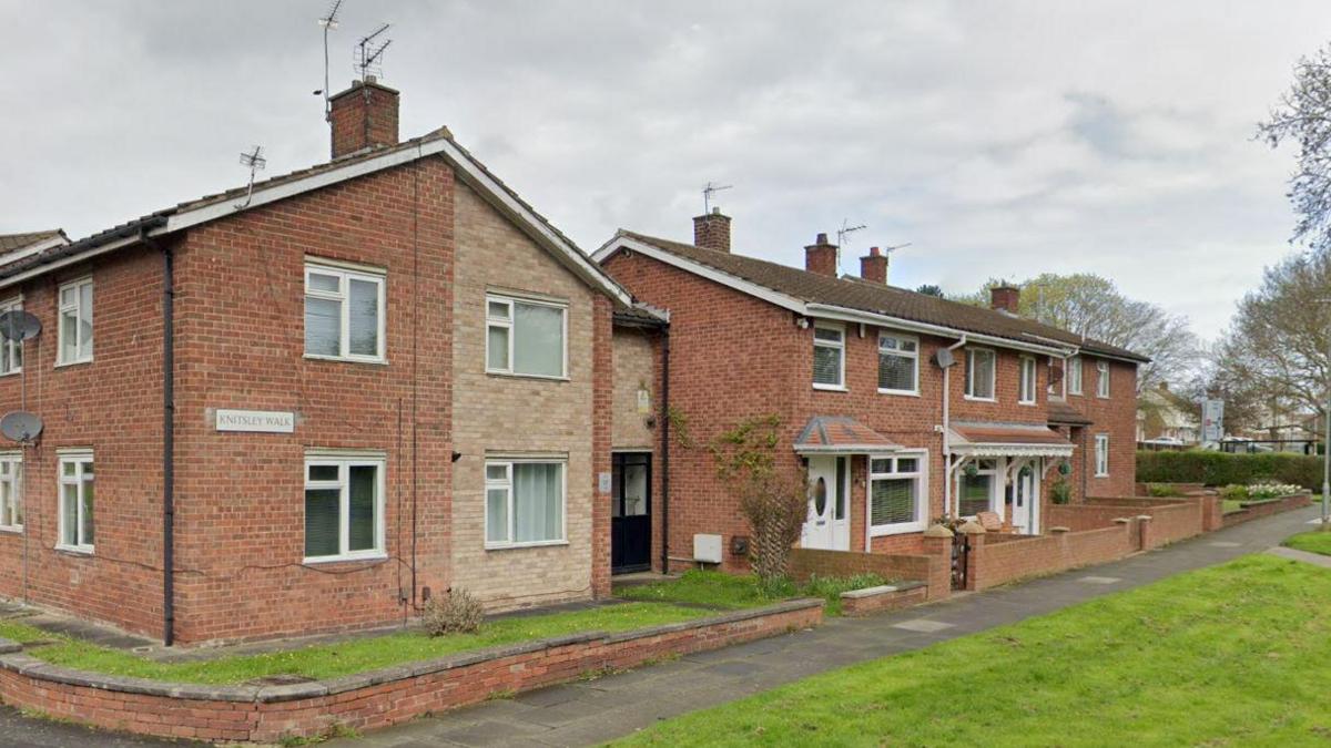 A public path passing by several houses on Knitsley Walk. Their are about six buildings, mostly semi-detached homes