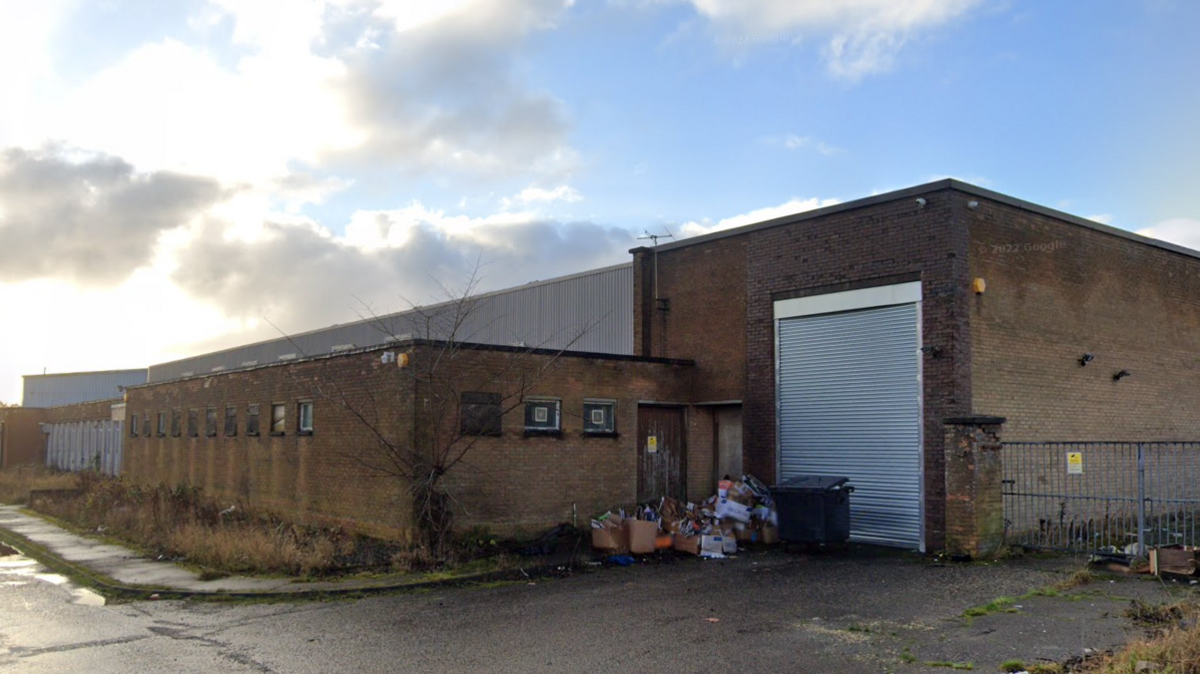 A screengrab of a large brick building with grey shutters.