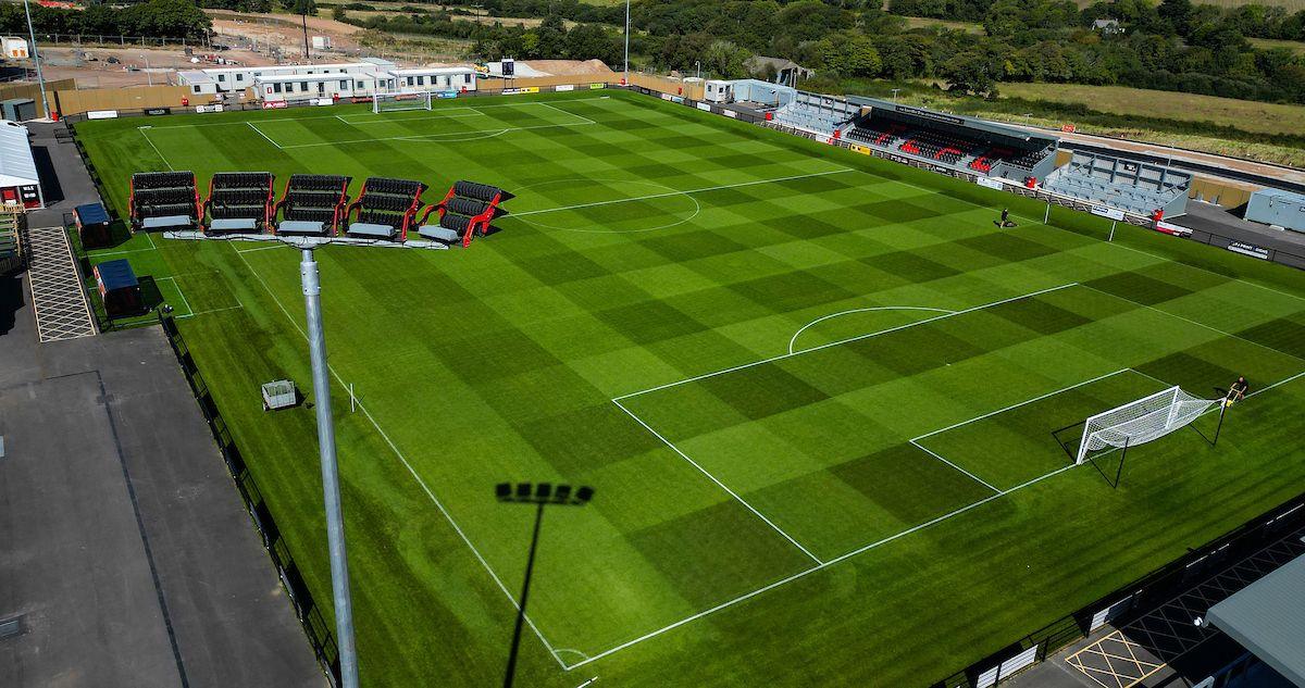 Aerial image of Truro City Stadium. The shot shows an empty pitch with goal posts either side. Seating lines the outside of the green pitch. 