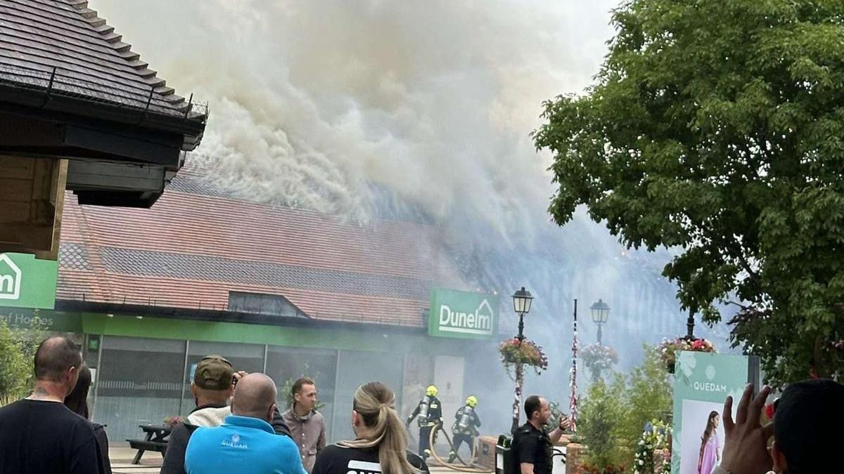 Fire smoking from Dunelm store with bystanders watching