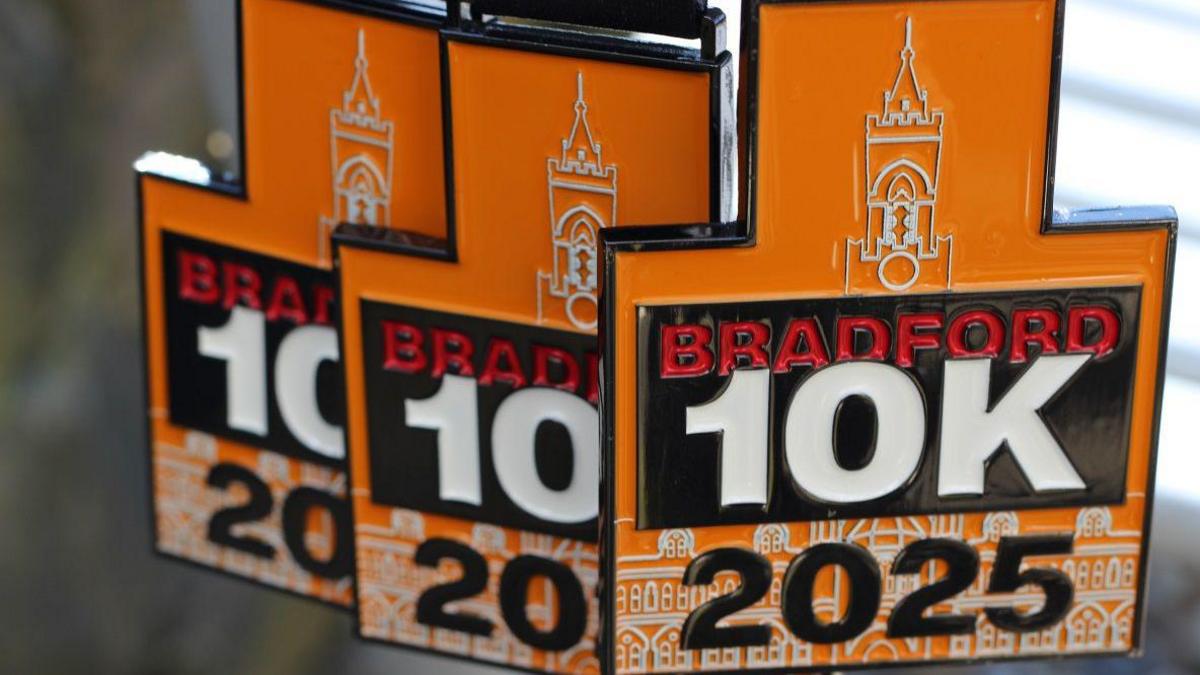 Three orange and black medals with the writing: Bradford 10k 2025
