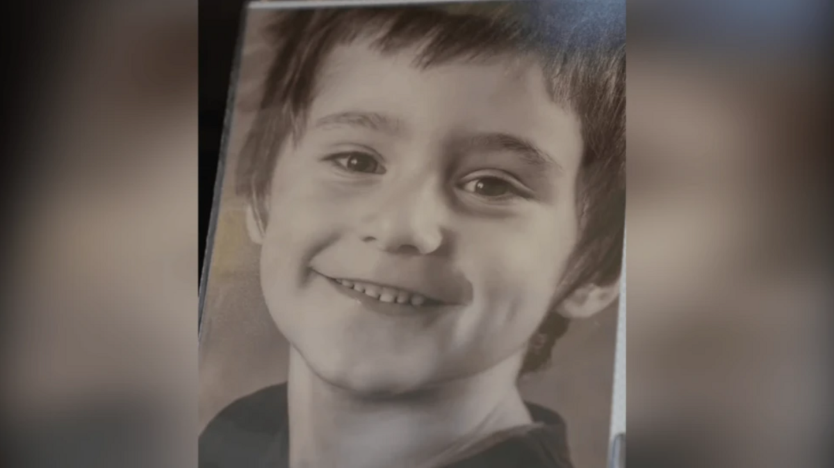 An image of a framed black and white photograph of Daniel Klosi, a four-year-old boy with short brown hair smiling at the camera