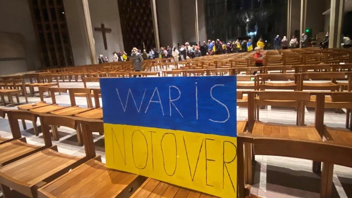 A blue and yellow banner has the words "War is not over" on it placed on chairs inside Coventry Cathedral