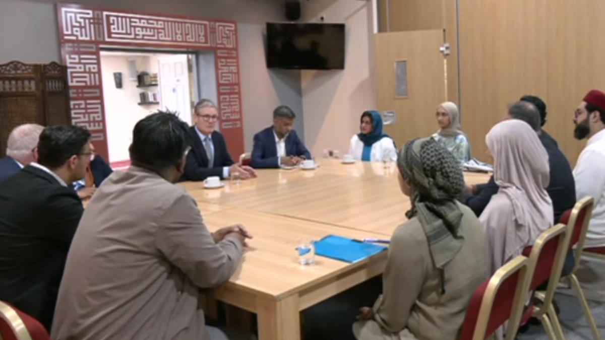 The prime minister sitting at a table talking to 12 people