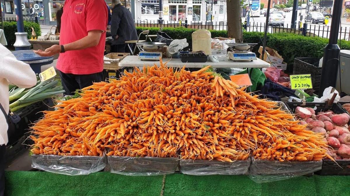 Large overflowing boxes of carrots are pictured on a market stall. 