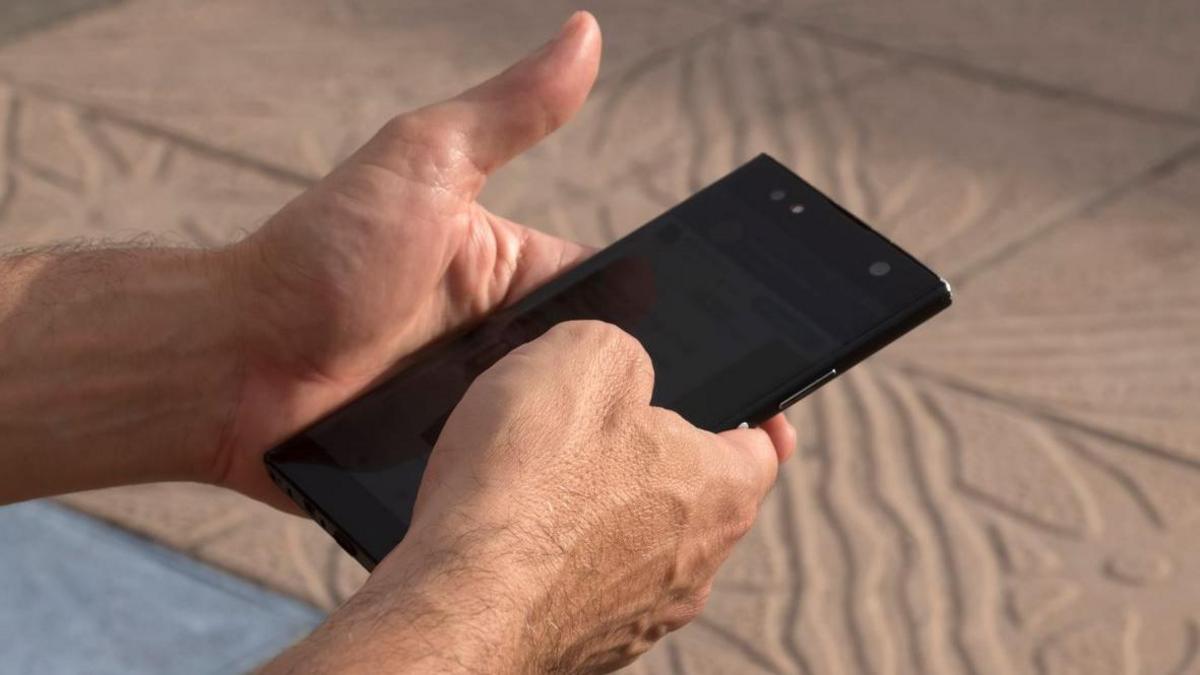 A model-posed image showing a man holding a mobile phone 