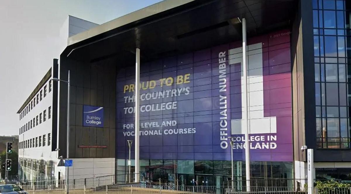 Street view image of Burnley College, a huge building with an imposing front entrance with white steel pillars and a large glass-fronted area with a huge purple sign saying 'Official no 1 college in England'