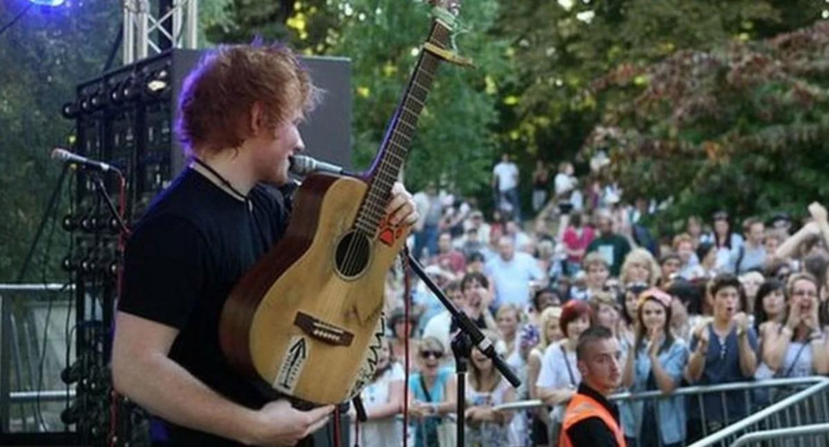 Ed Sheeran on stage with a guitar in front of a crowd at Ipswich Music Day