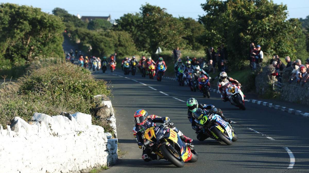 Davey Todd followed by Mike Browne on the road, with a long line of riders following behind.