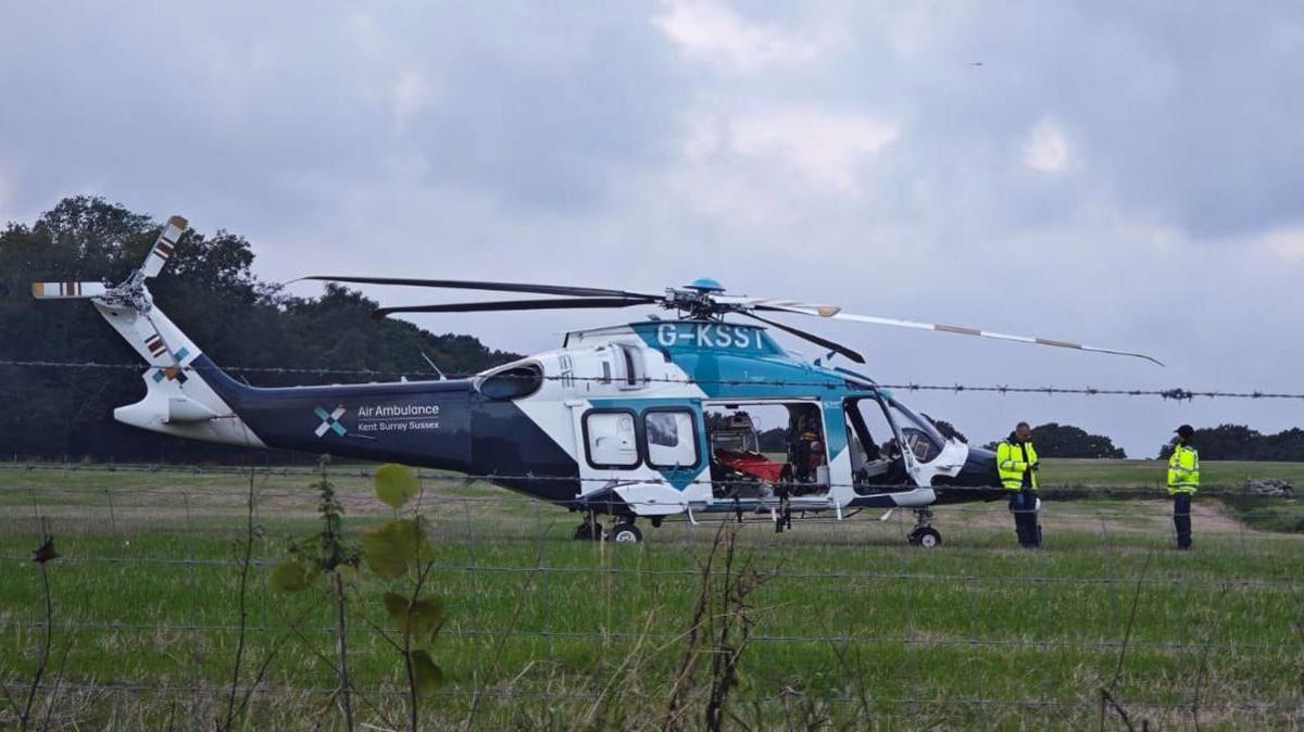 A blue and white air ambulance sits on a field