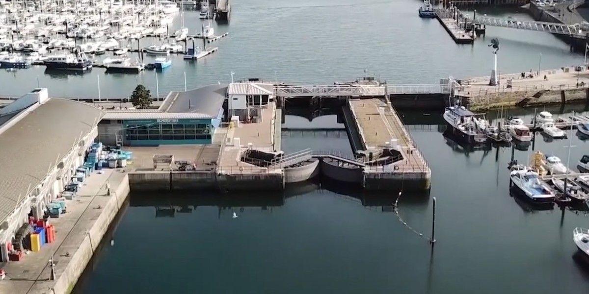 A general view of Sutton Harbour which shows the main lock gates and pedestrian bridge crossing from the Barbican