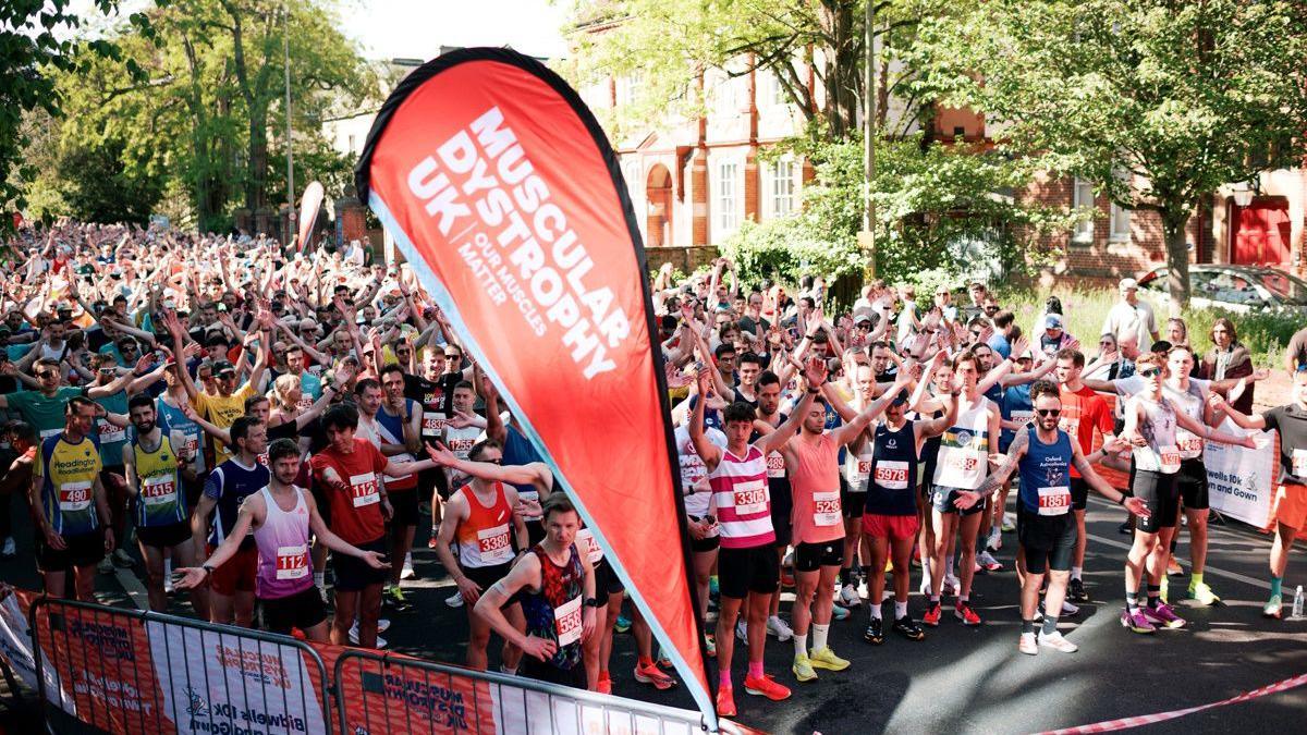 People waiting at the start line ready to take on the 10k race in Oxford. It is a sunny day.