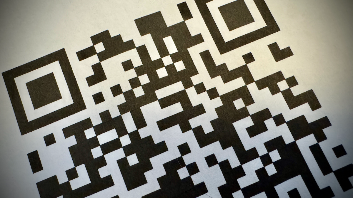 A square black and white QR code made up of random geometric shapes