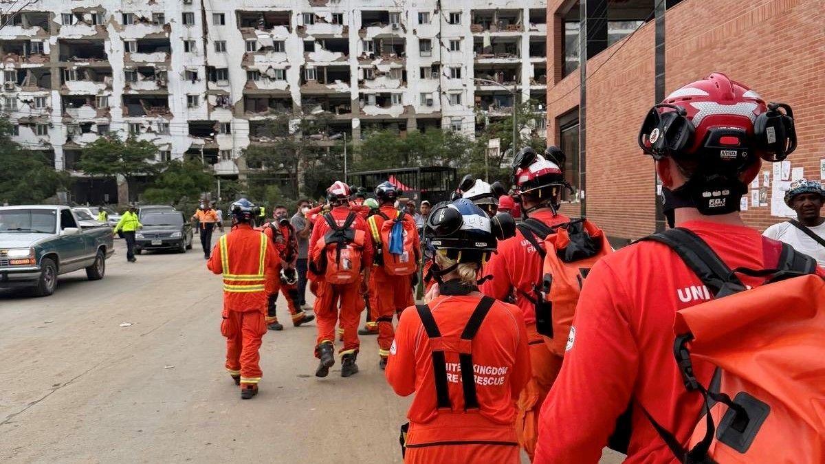 Firefighters in orange uniforms walking away from the camera in Venezuela.