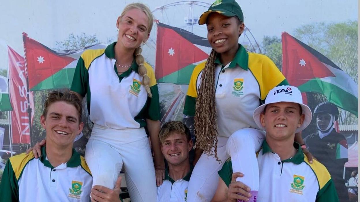 Three male members of the South African tent pegging squad chair two women on their shoulders, with all five dressed in white, green and yellow South Africa kit featuring a crest over their left breast