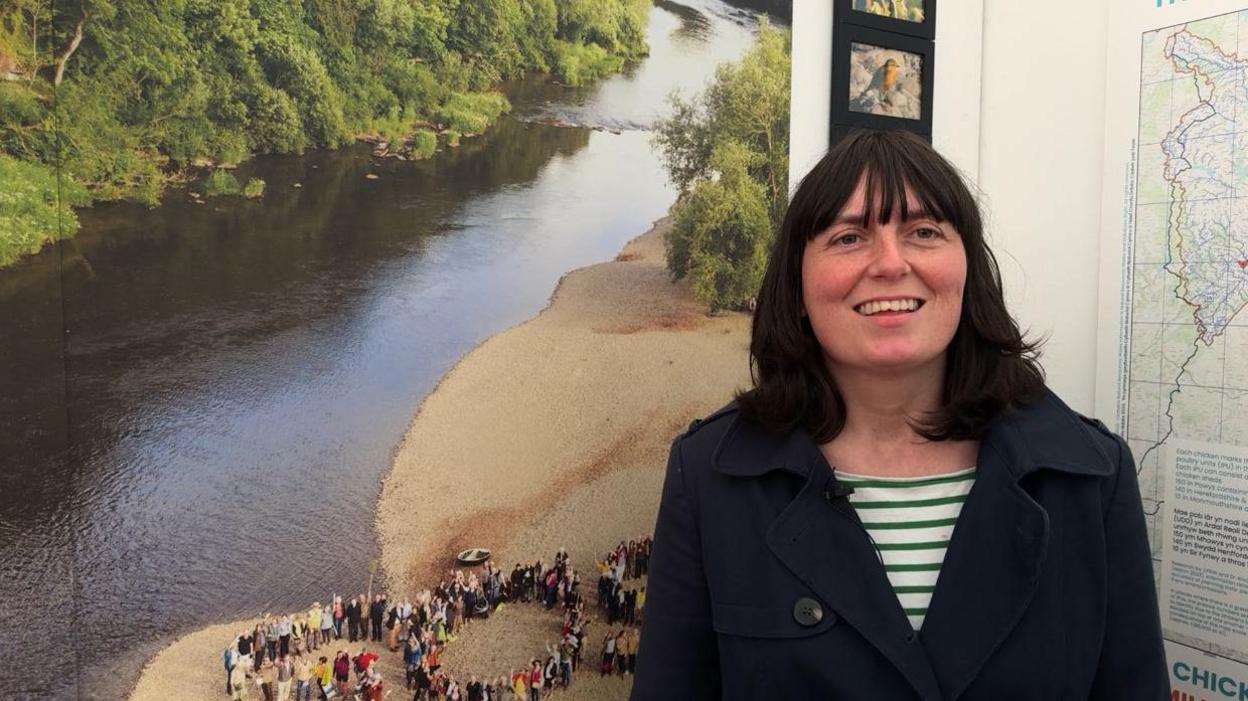 Nicola Cutcher standing in front of a picture of the River Wye