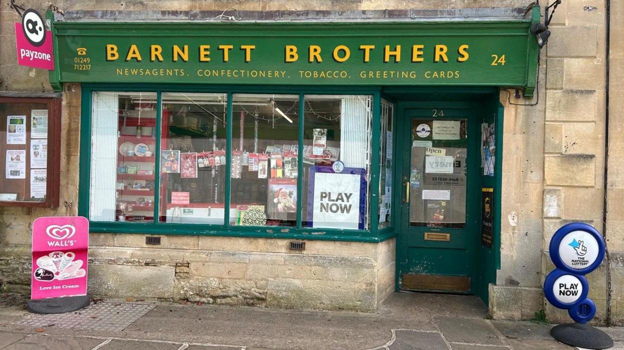 A newsagent shop called Barnett Brothers. The shop sign has been repainted in dark green with yellow lettering