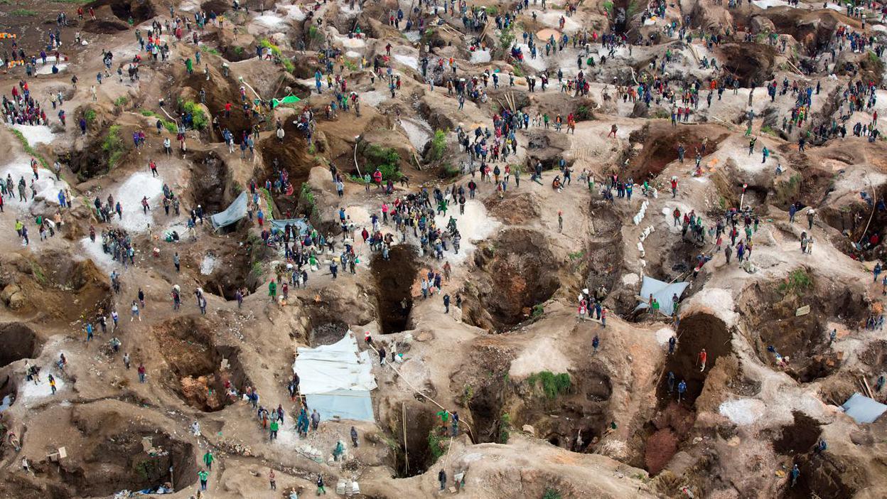 An aerial view of a coltan mine with open pits dotted across the landscape.