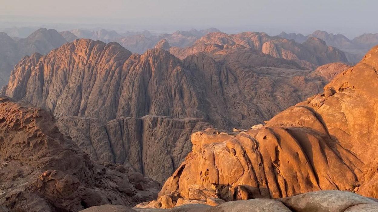 The mountains at dusk, from Jebel el Ahmar in 2024. Light hits the top of a rocky mountain range, which stretches into the distance