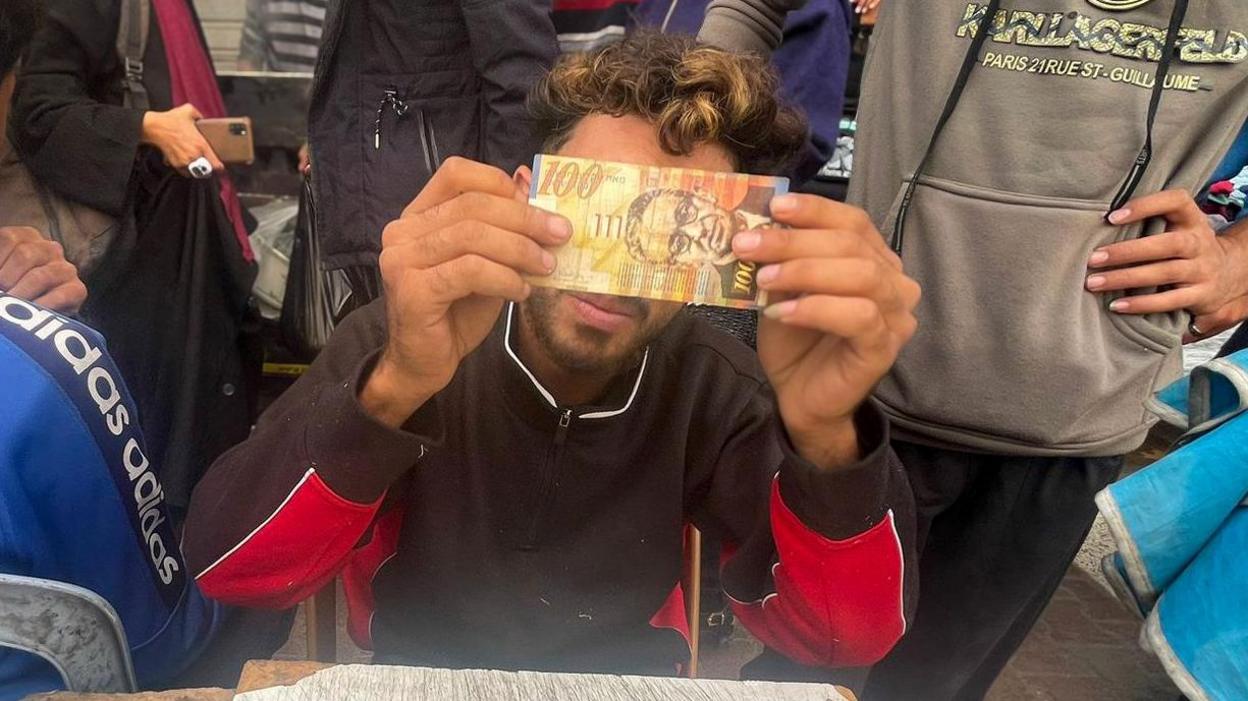 Baraa Abu al-Aoun repairing bank notes in Gaza