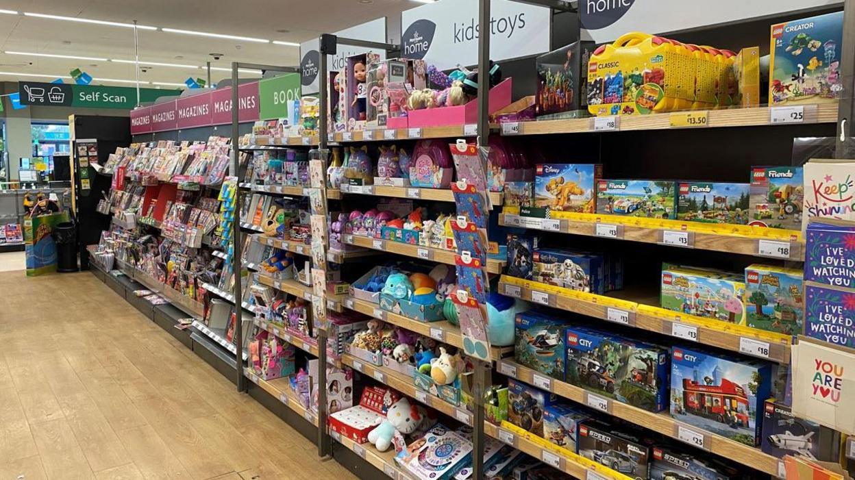 A supermarket aisle displaying children's toys and magazines, including children's magazines. 