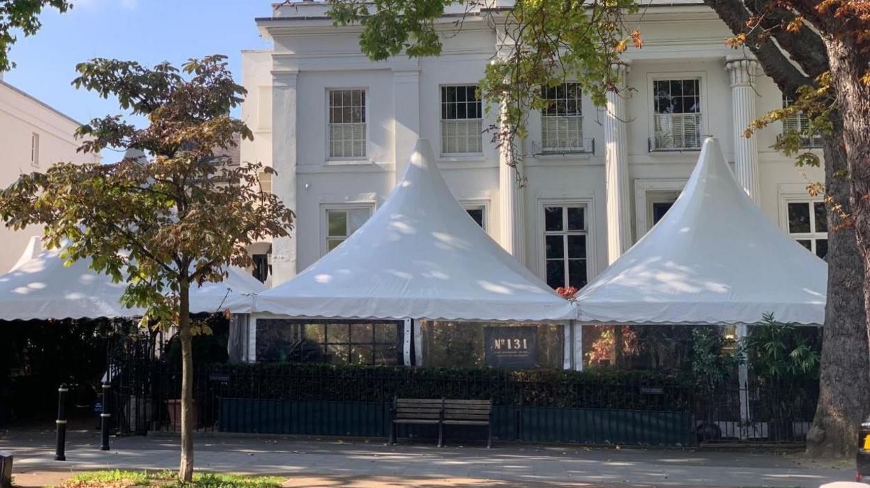 Three white tents erected outside of a white regency building