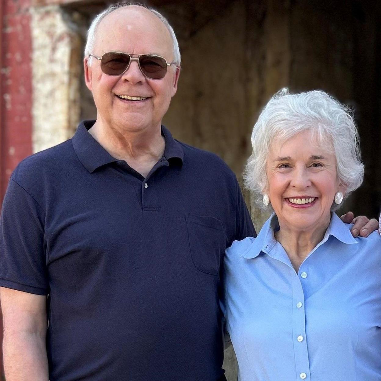 Photo showing Harper Lee's nephew, Dr Edwin Lee Conner on the left -- smiling & with sun glasses and wearing dark blue shirt and niece, Molly Lee in pale blue shirt, also smiling. Molly has grey short hair and is wearing large pearl earrings