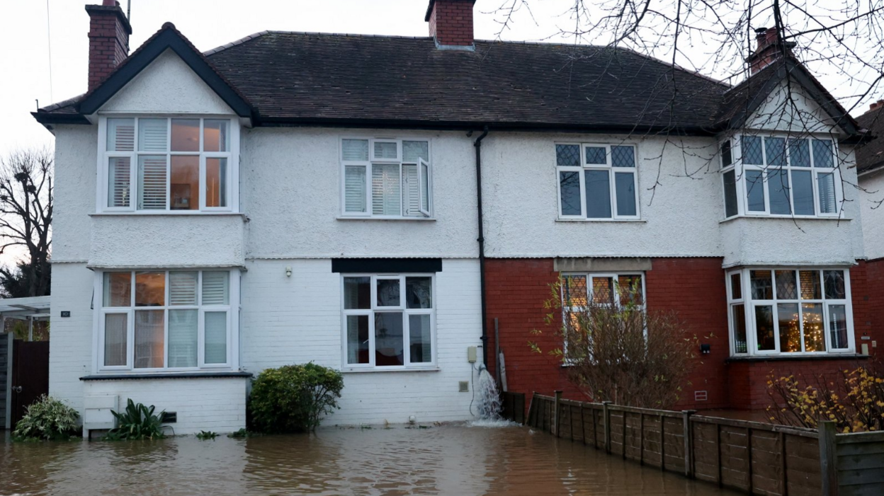 Brown water is seen filling the front garden of a semi-detached house in Hereford 