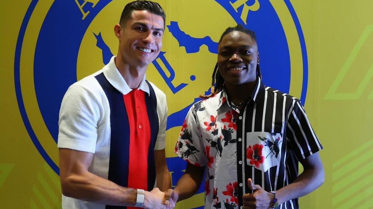 Tanzania's star striker Clara Luvanga shakes hands with Portuguese star Ronaldo in front of a banner showing the club crest of Saudi club Al-Nassr