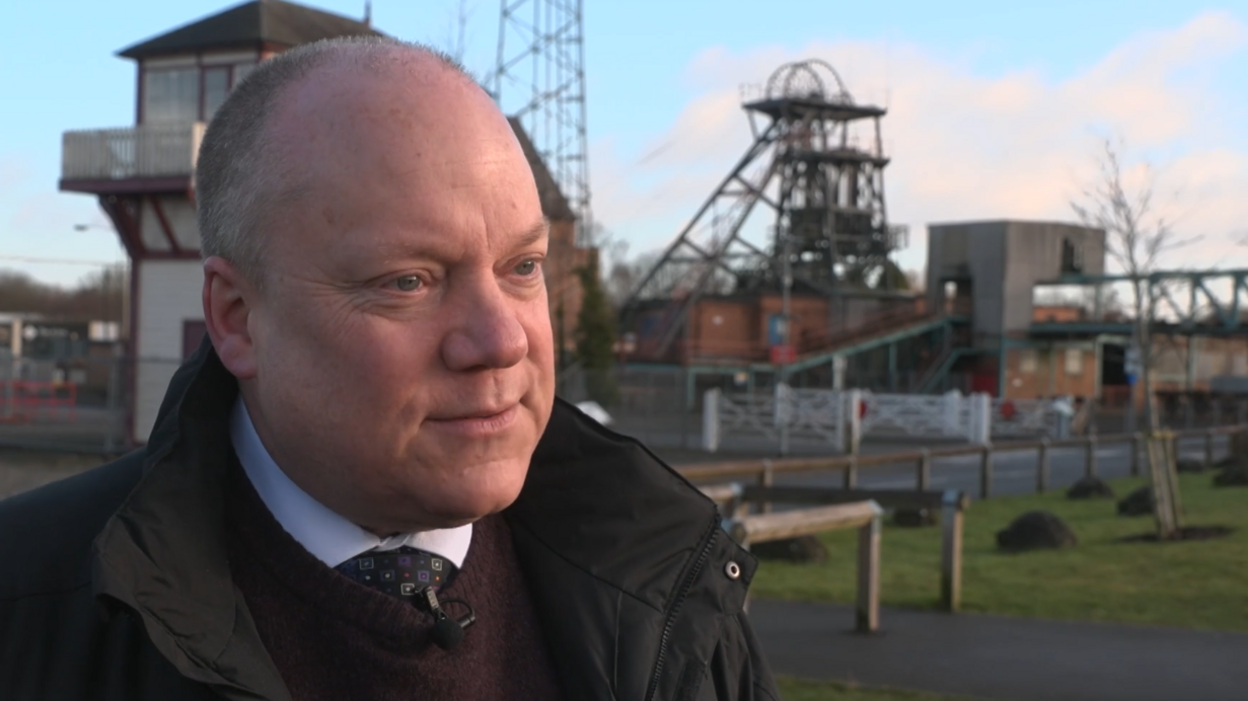 Mr Prior smartly dressed in a tie and shirt in front of an old mining facility 