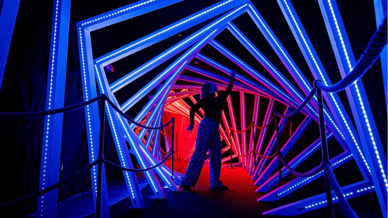 A woman stands inside a colourful light tunnel at Wake the Tiger in Bristol