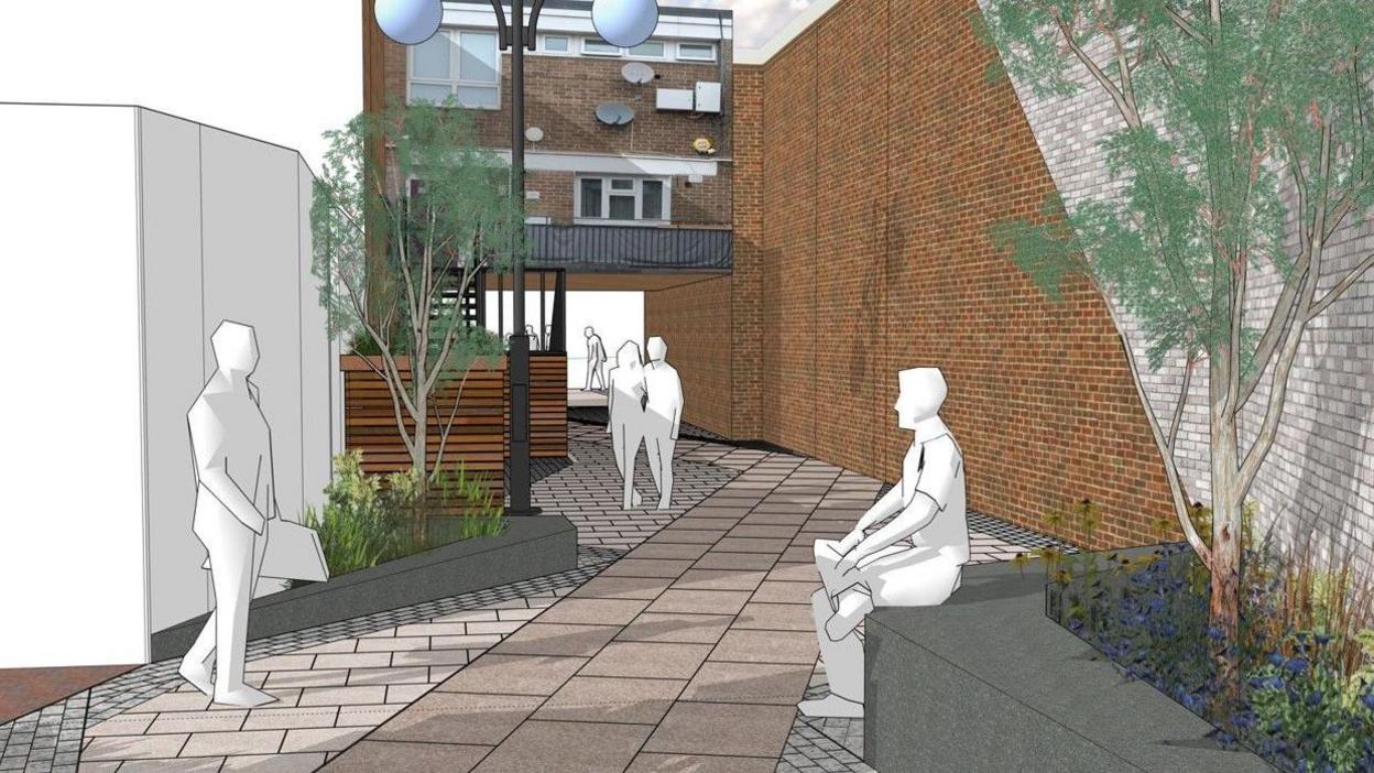 A handful of people are seen, with some standing and one person seated. A walkway goes through the middle of the photo, with walls to the left and right.