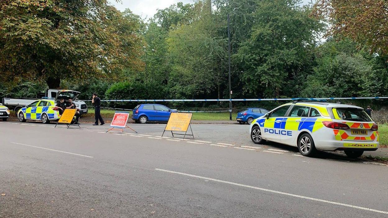 Two police cars and police tape are seen blocking off the entrance to Parrys Lane in Bristol