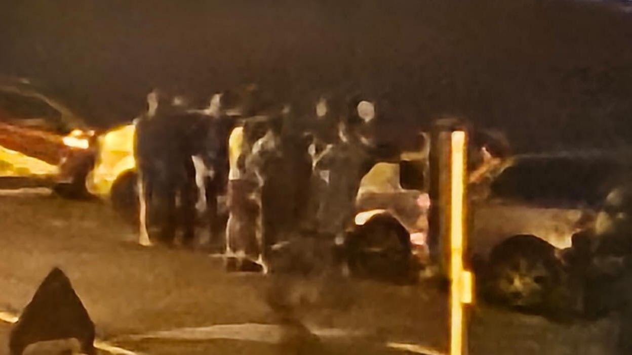Young people gathering on Paignton sea front at night with noisy adapted cars