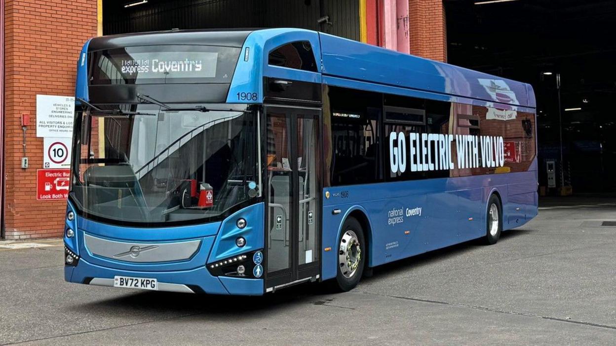 National Express Coventry bus. The bus is blue with a sign on the side which says "Go Electric Volvo" 