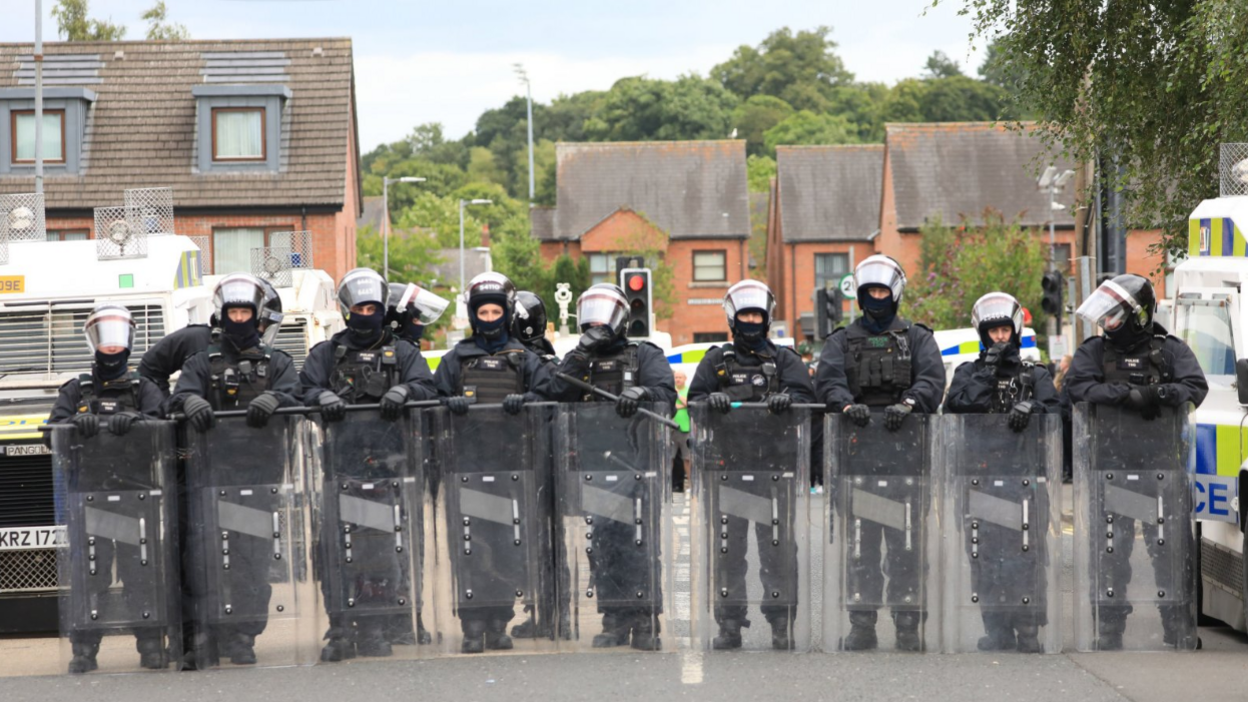 Riot police form a line after people taking part in an anti-Islamic protest make their way through the area following a protest outside Belfast City Hall