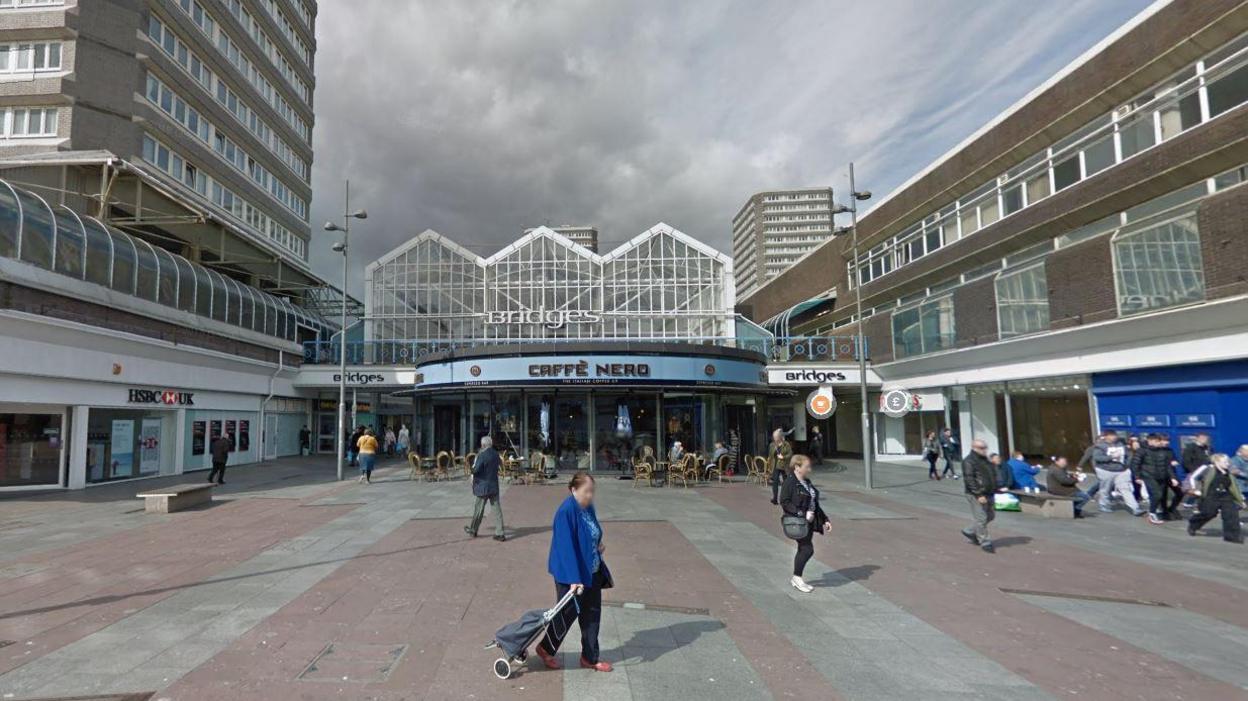 People walking past the entrance to the Bridges Shopping Centre. Caffé Nero is at the entrance.