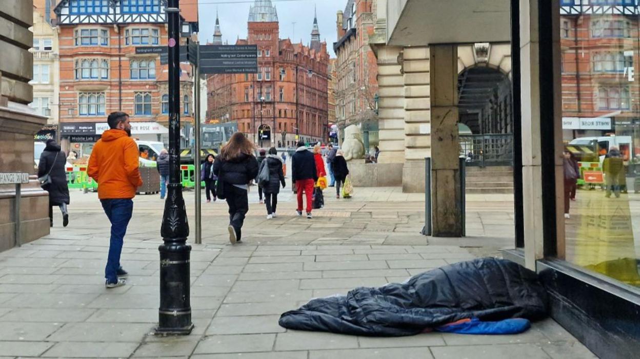 A sleeping bag on the ground, apparently with someone inside, near to Market Square in Nottingham