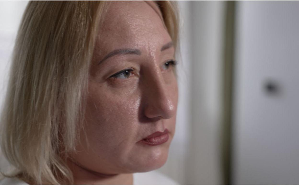 A woman with a blonde bob looks into the distance.