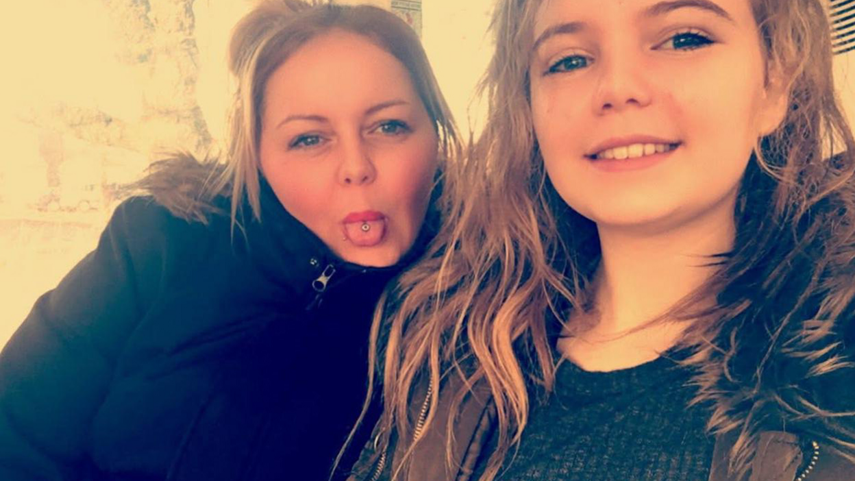 A woman sticks her pierced tongue out next to her teenage daughter