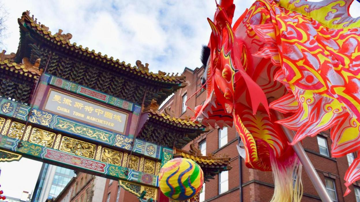 A red and yellow Chinese dragon is held aloft underneath the Chinatown archway in Manchester. 