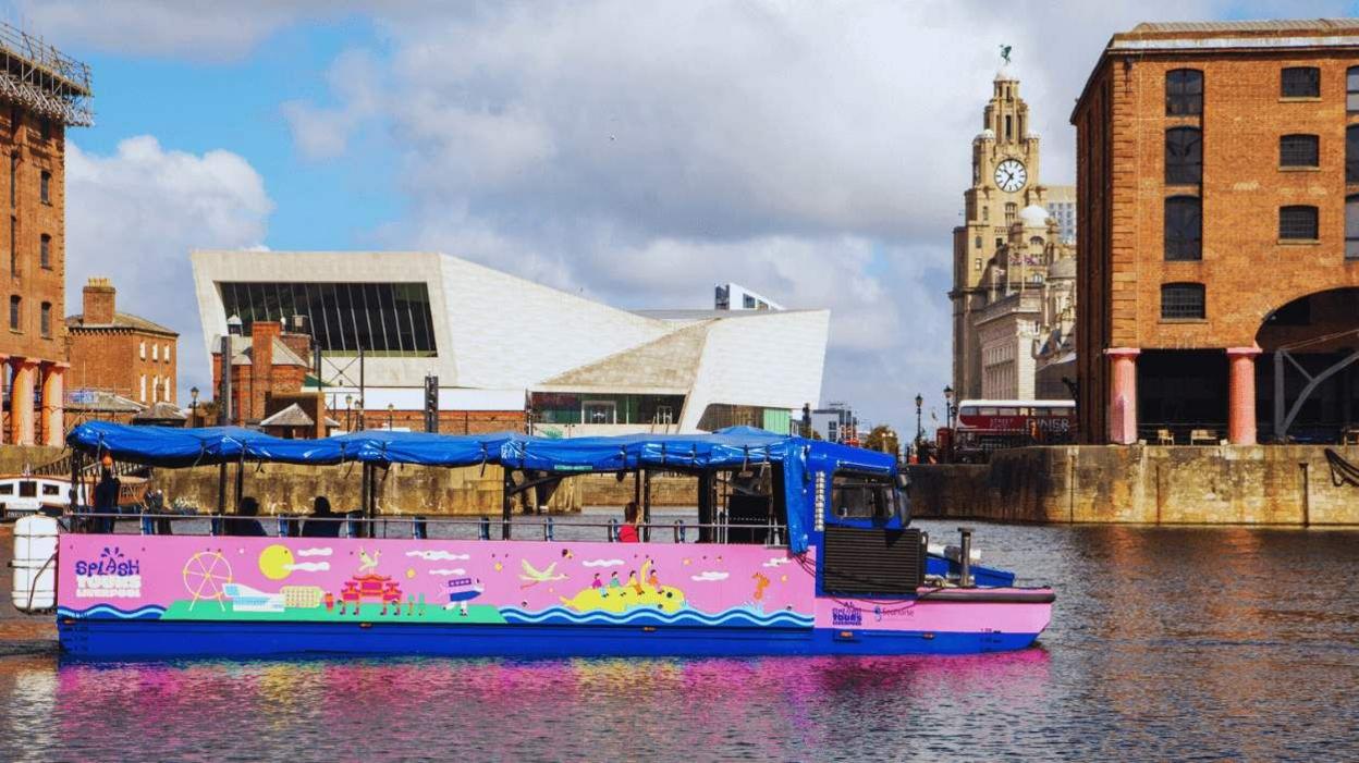 A pink and blue boat with colourful cartoons painted on its side