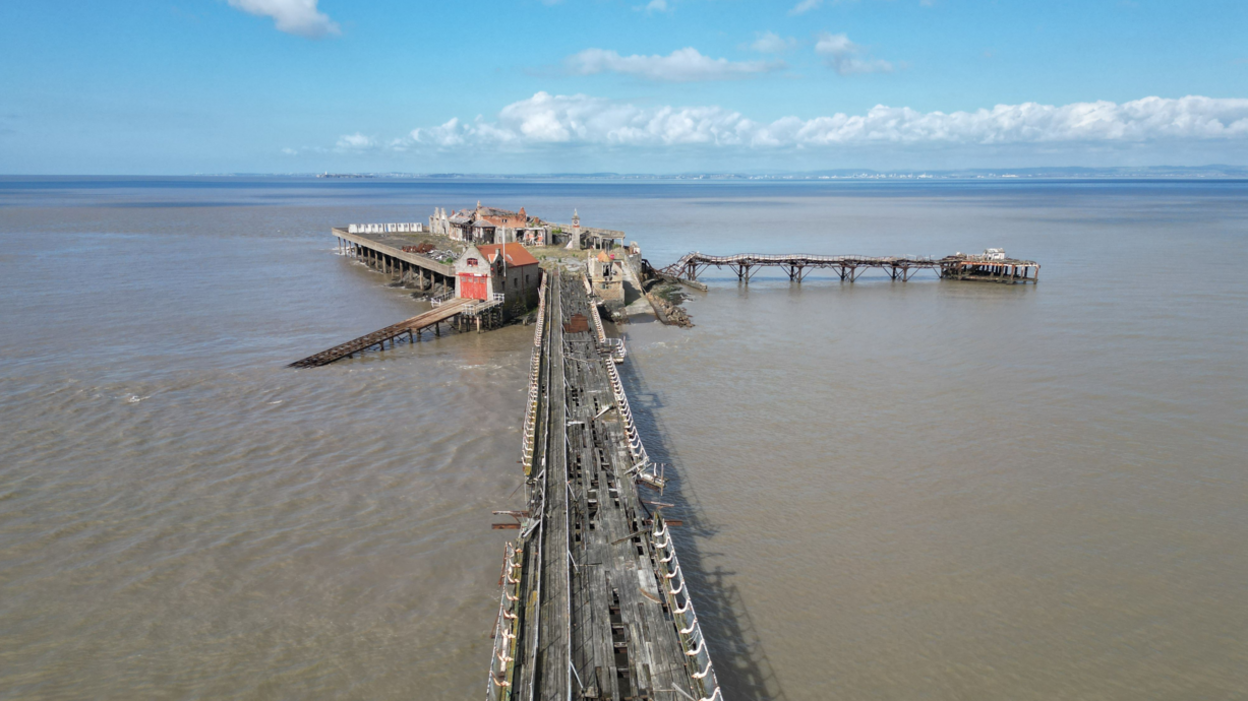 A wide shot showing the bridge and pier in poor, crumbling condition