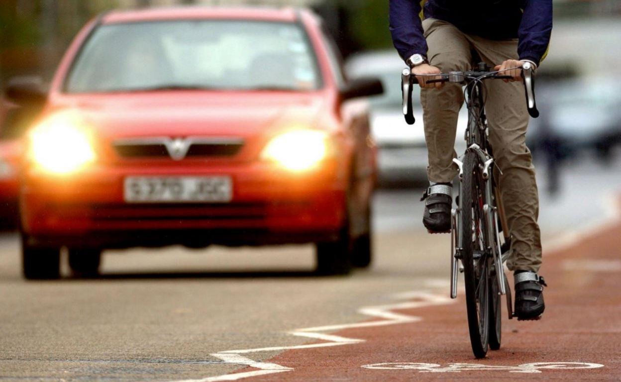 An anonymous cyclist is in a cycle lane on a main city road, as cars pass him on his right