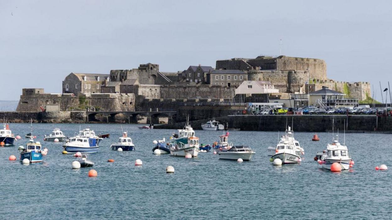 Castle Cornet overlooking a harbour with several boats anchored in the water.