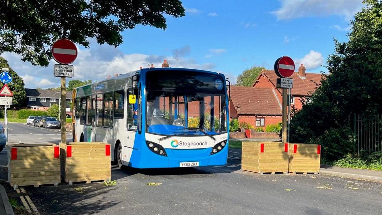 A bus driving through the low traffic neighbourhood barrier