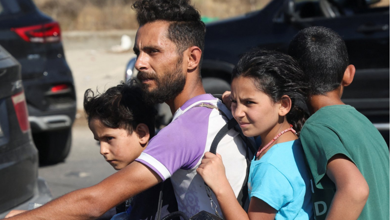 A man and children ride a motorcycle in heavy traffic as they drive north from Lebanon's southern city Sidon fleeing Israeli bombardment