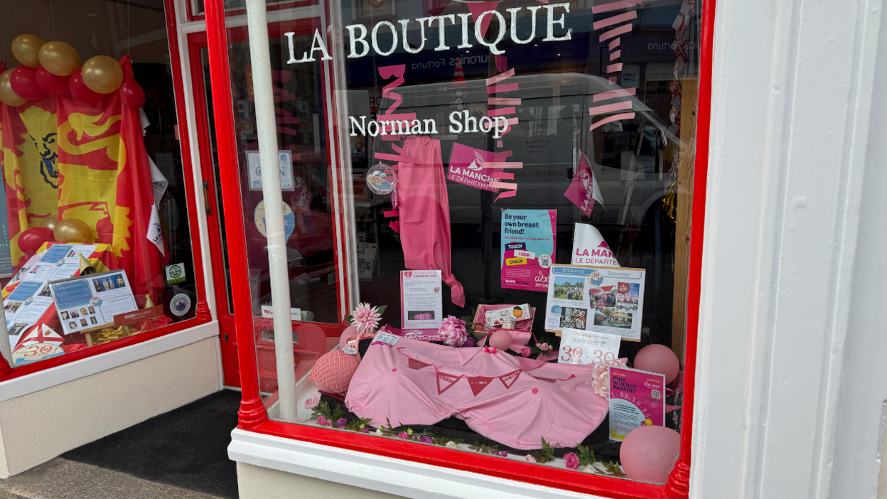 The photo show pink printed bunting draped over something to create the shape of breasts in a shop window. There are also pink balloons on display.