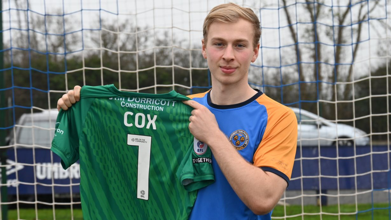 Matthew Cox poses with a Shrewsbury Town shirt with number one on the back