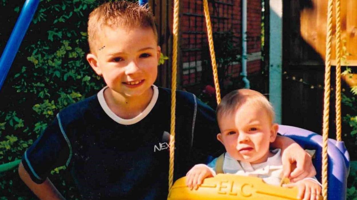 Two young boys playing with a swing 